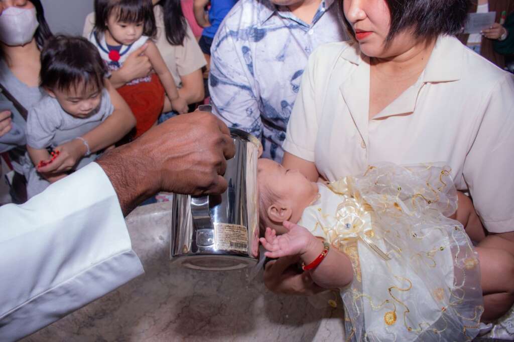 Baby being baptized at the font with family