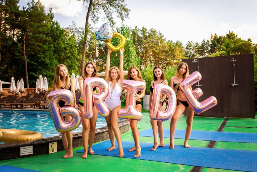 Friends holding BRIDE balloons at a despedida