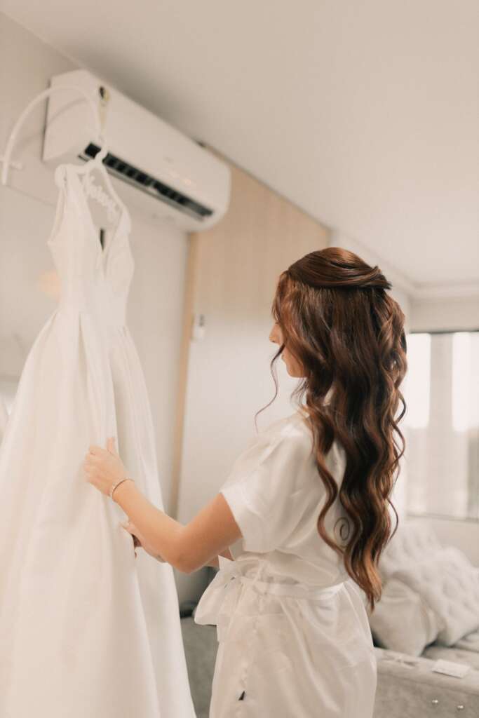 Bride in a robe holding her wedding dress on a hanger