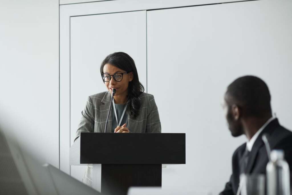 Woman speaking at a podium to an audience