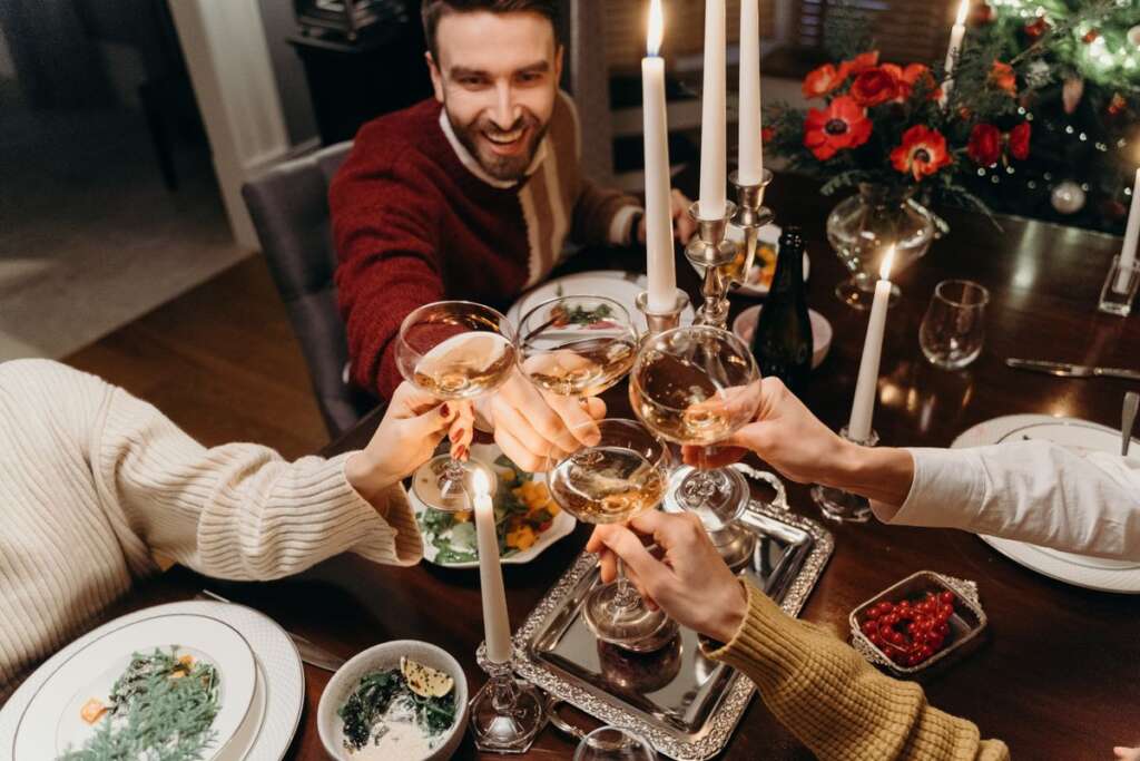 Friends toasting by candlelight at a Christmas dinner