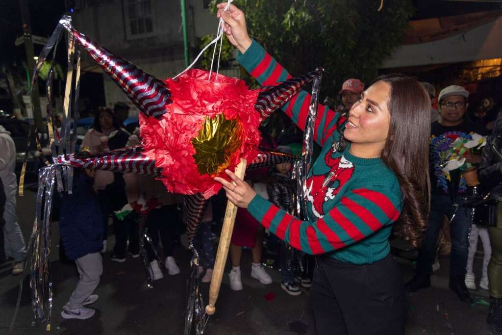 Girl swinging at a piñata during a posada